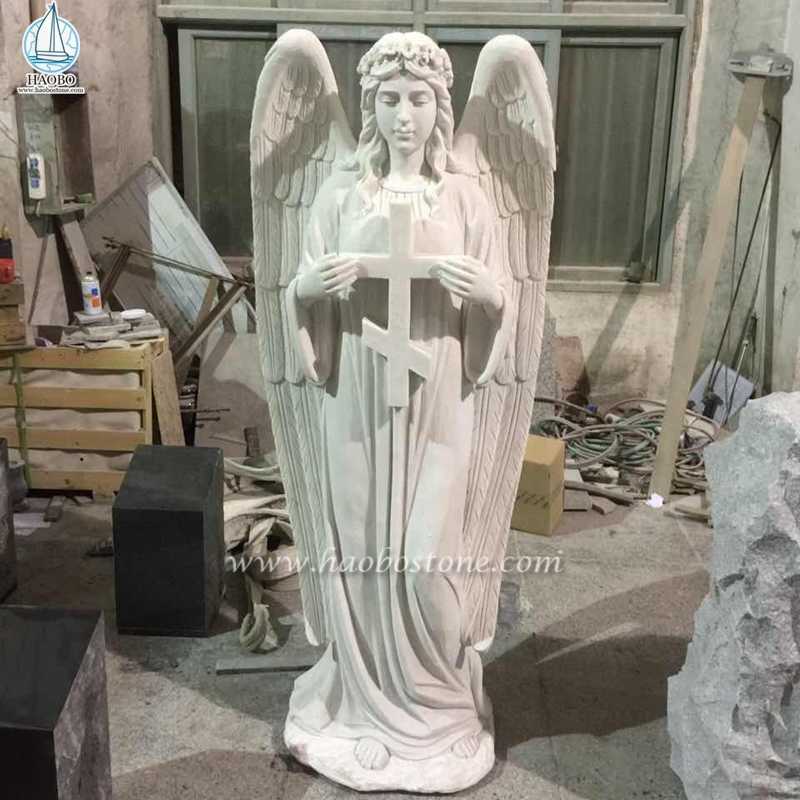 Белый мраморный крест со скульптурой стоящего ангела
